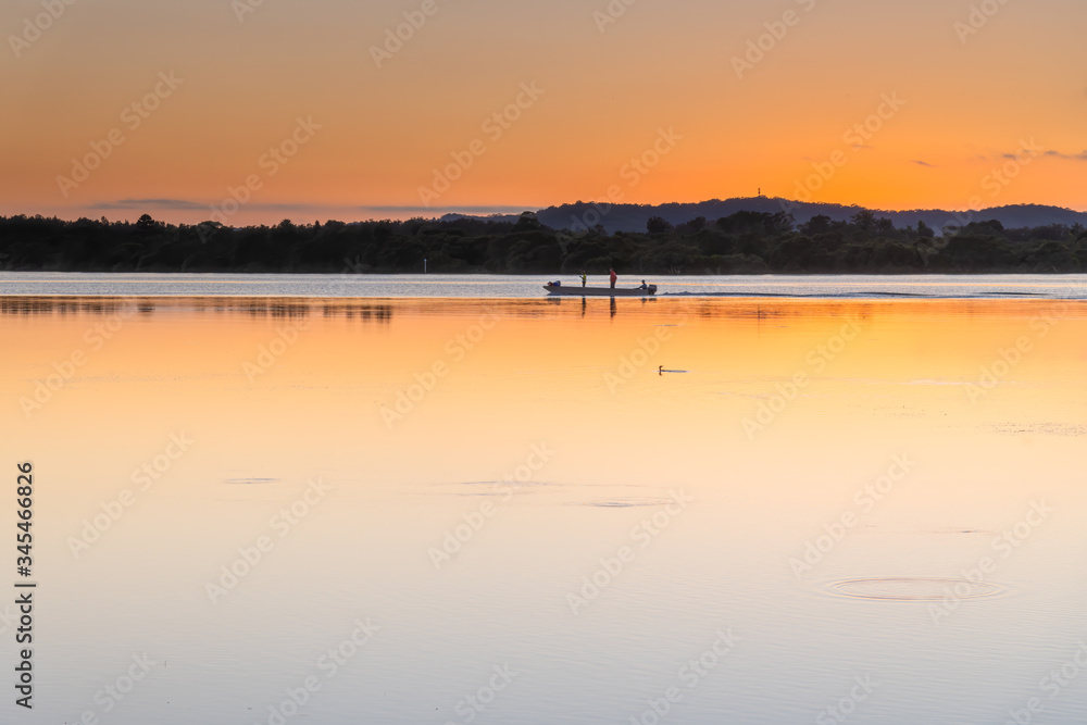 Soft Shades of an Orange Sunrise over the Bay with Three Fisherman in Boat