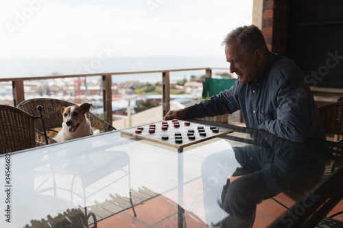 Senior man playing checkers on his terrace 