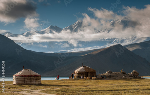 Fotografie The yurt village in front of Karakul Lake in Xinjiang Uighur Autonomous Region of China is the highest lake of the Pamir plateau, with Muztagh Ata peak of the Kunlun mountains, in the background