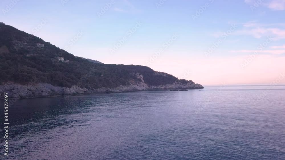 Forward aerial shot over calm sea and next to a rocky shore during blue hour in Greece Forward aerial shot over calm sea and next to a rocky shore during blue hour in Greece