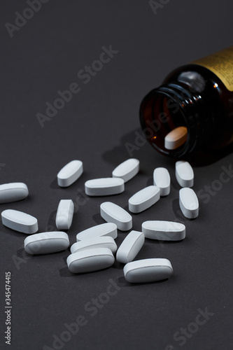 many white tablets on a gray background made of dark glass jars