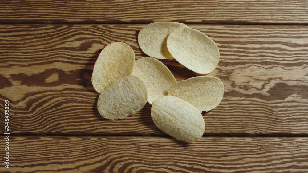 TOP VIEW: Potato chips appear one by one on wooden surface. Stop motion animation TOP VIEW: Potato chips appear one by one on wooden surface. Stop motion animation