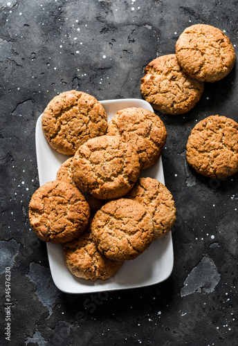 Delicious oatmeal cookies with walnuts on a dark background, top view