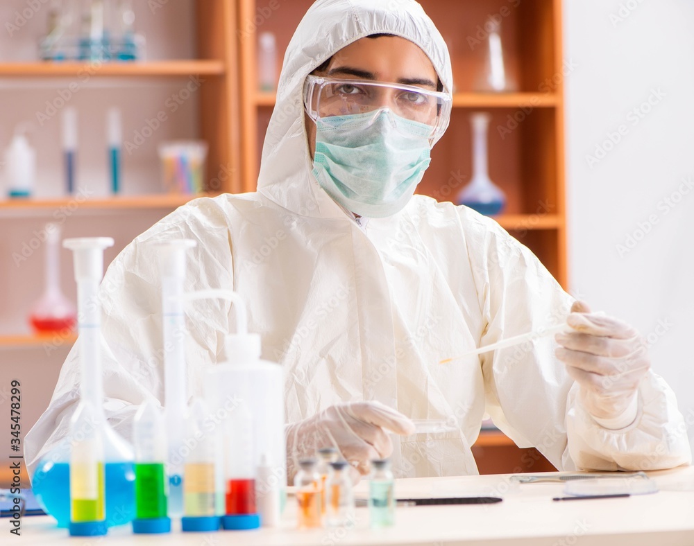 Young biochemist wearing protective suit working in the lab Young biochemist wearing protective suit working in the lab
