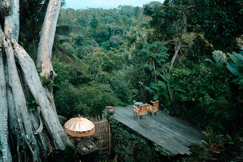 Scenic lounge zone with wooden chairs on a wooden platform, green deep canyon viewpoint. House in jungle Bali, Ubud.