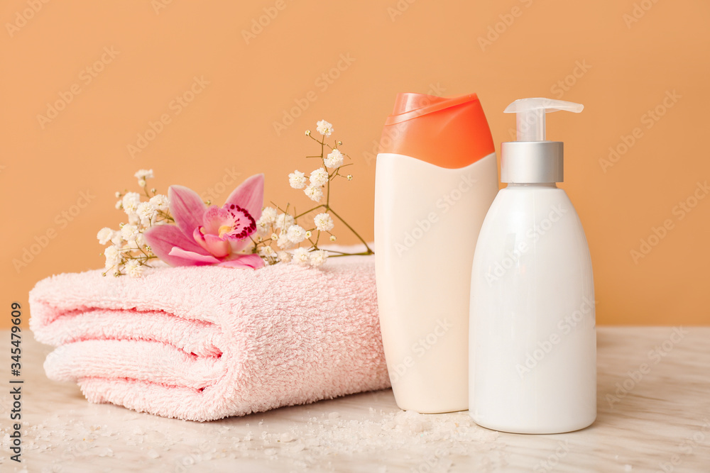 Shower gels, towel and flowers on color background Shower gels, towel and flowers on color background
