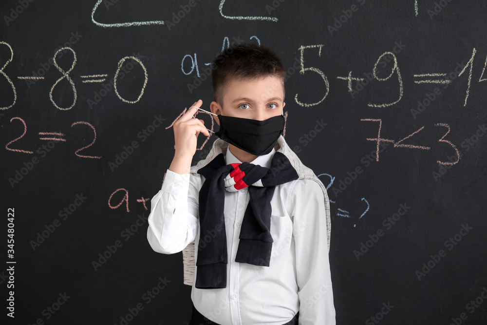Little schoolboy in protective mask in classroom. Concept of epidemic
