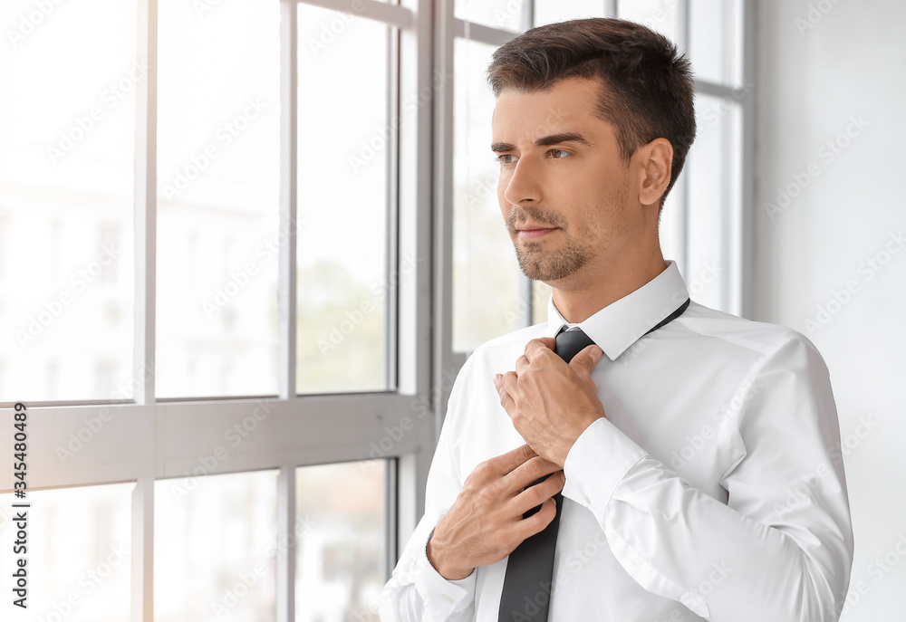Fototapeta premium Portrait of handsome businessman near window in office