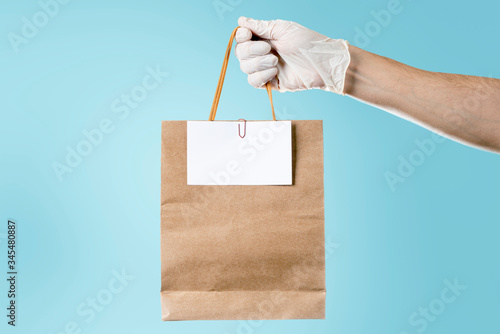 Delivery man holding package with ticket. Concept deliveries, groceries and food supplies. Cyan background.