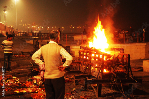 People look at the funeral pyre that night. The ceremony of the cremation of Manikarnika Ghat on the banks of the Ganges river in Varanasi, India