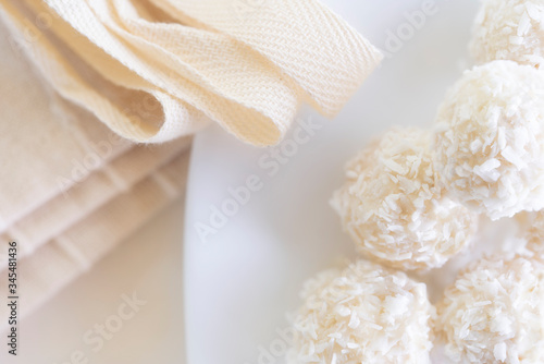 Candies in plate covered by chocolate, shredded coconut and kitchen towel on rustic wooden background.