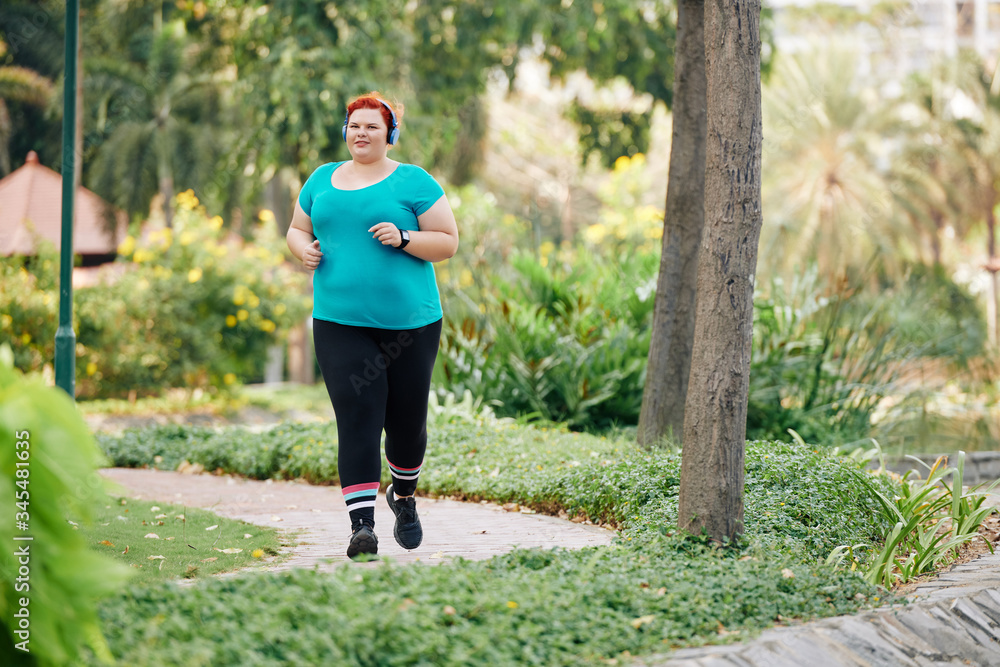 Plus size young woman enjoying running in park in the morning Plus size young woman enjoying running in park in the morning