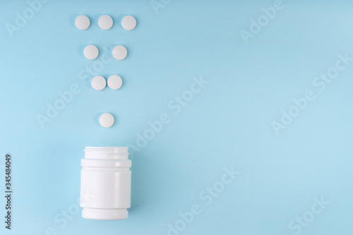 Exclamation point sign, mark from pharmaceutical medicine pills. Creative layout of tablets and bottle on blue. Exclamation symbol. Medicine, healthcare concept. Copy space, flat lay
