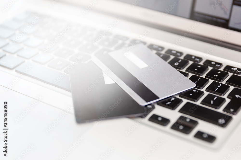 Credit cards lie on a laptop keyboard. The financial crisis and panic during the coronavirus pandemic. Quarantine online purchases. Close-up. Flare. Credit cards lie on a laptop keyboard. The financial crisis and panic during the coronavirus pandemic. Quarantine online purchases. Close-up. Flare.