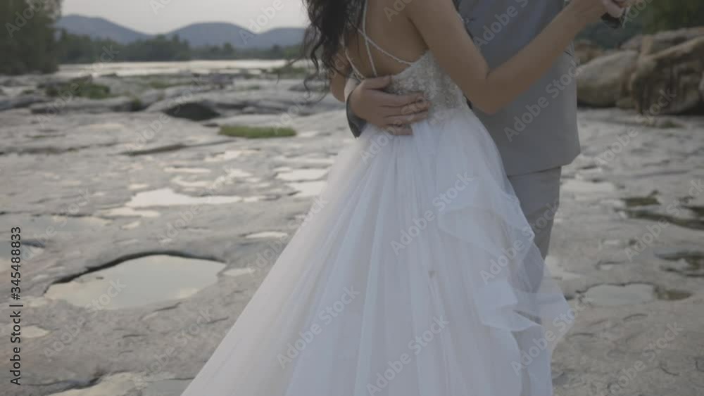 Newly wedding couple dancing in a close embrace on a river bed next to a river Newly wedding couple dancing in a close embrace on a river bed next to a river