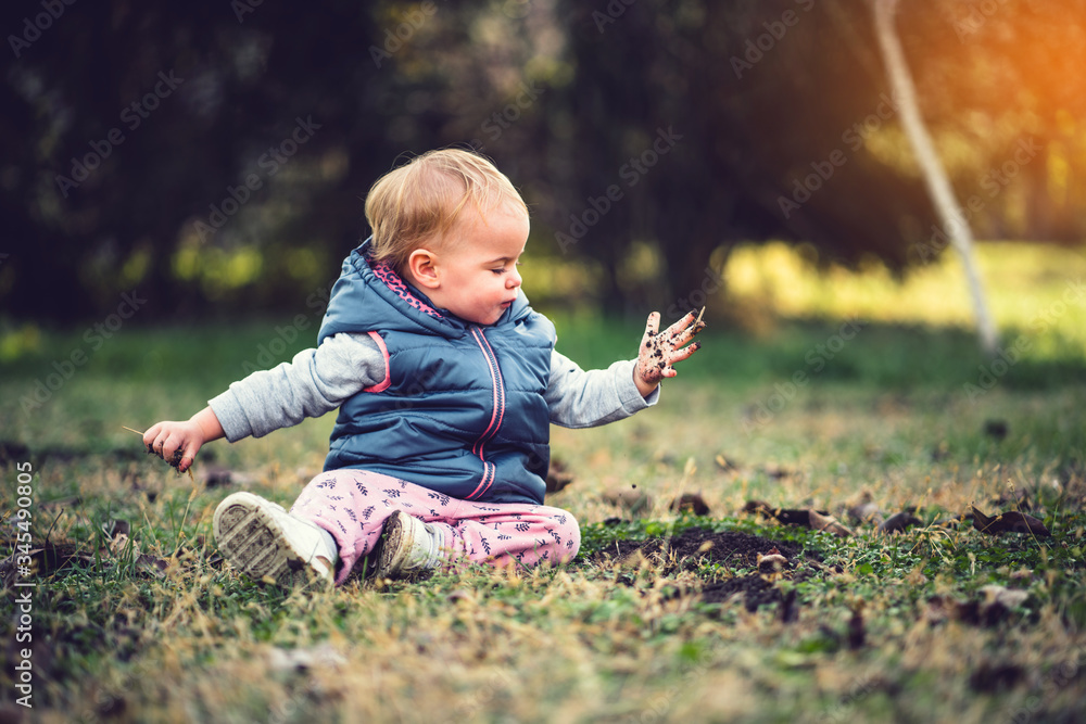 Toddler playing in grass and mud. Dirty hands, nature and immunity concept. Toddler playing in grass and mud. Dirty hands, nature and immunity concept.