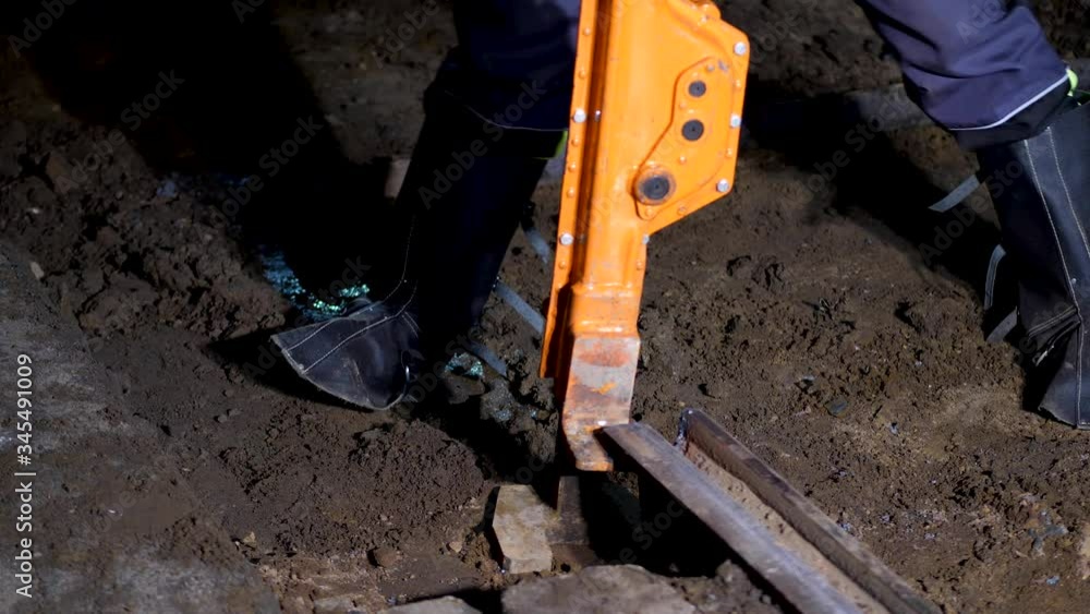 Construction workers using heavy duty equipment to lift a rail embedded