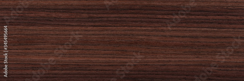 Contrast rosewood veneer background in dark color. Natural wood texture, pattern of a long veneer sheet, plank.