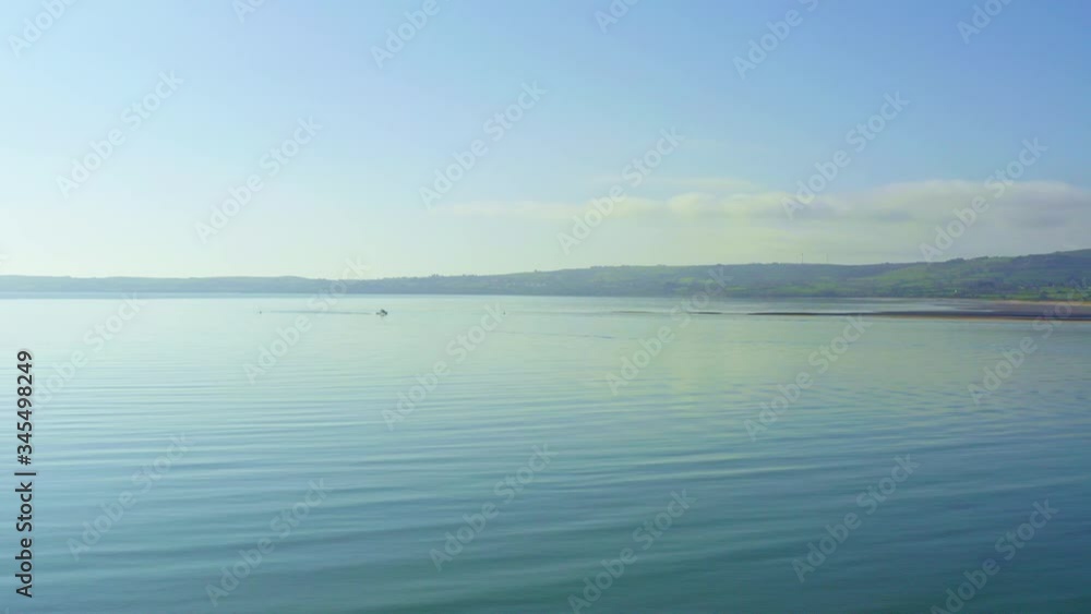 Aerial establishing shot of calm ocean water during summer, boat in background Aerial establishing shot of calm ocean water during summer, boat in background