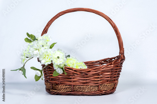 Brown wicker basket with flower arrangements on the handle of the basket.