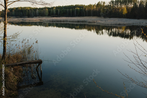 Fishing rod on a bridge on pond background. Spinning with reel on pier river. Misty morning on lake. wild nature. The concept of rural recreation. Article about fishing day. Vintage banner for design. © Serhii