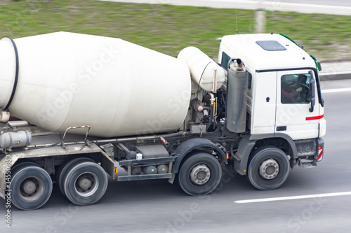 Concrete white mixer truck rides on city highway.