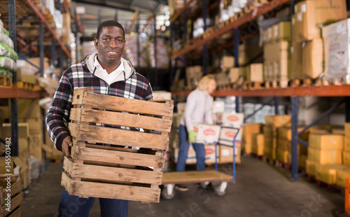 Smiling man carrying boxes in warehouse