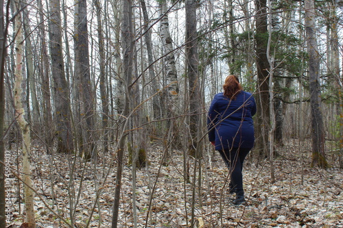 A full girl walks in the thick forest in spring