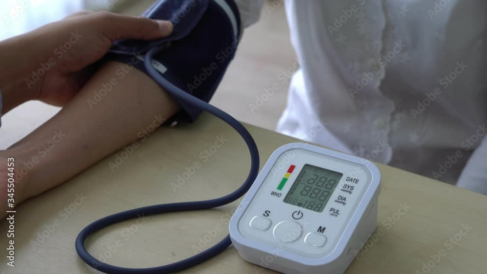 close up view of doctor using automatic sphygmomanometer or blood pressure monitor to measure blood pressure of patient who has hypertension and come visit at clinic. healthcare and medical concept close up view of doctor using automatic sphygmomanometer or blood pressure monitor to measure blood pressure of patient who has hypertension and come visit at clinic. healthcare and medical concept
