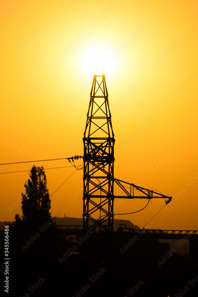 silhouette of an energy tower at dawn with the sun in the background. concept of solar, ecological and renewable energy.