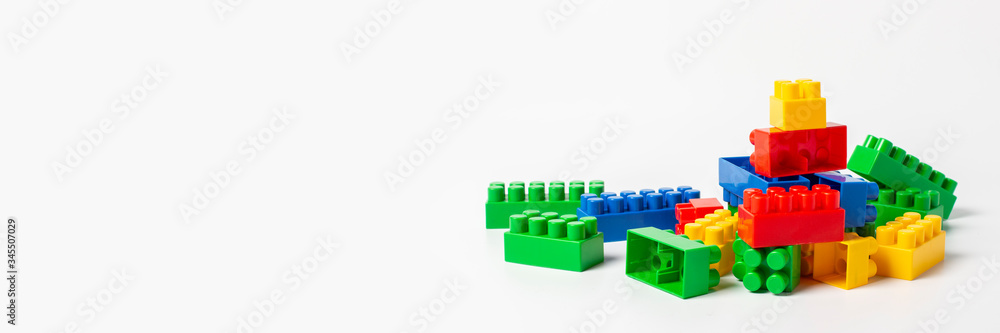 Multicolored designer parts on an isolated white background. Educational toys, logic. Banner Multicolored designer parts on an isolated white background. Educational toys, logic. Banner