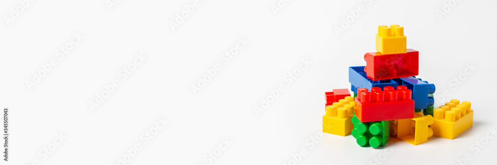 Multicolored designer parts on an isolated white background. Educational toys, logic. Banner Multicolored designer parts on an isolated white background. Educational toys, logic. Banner