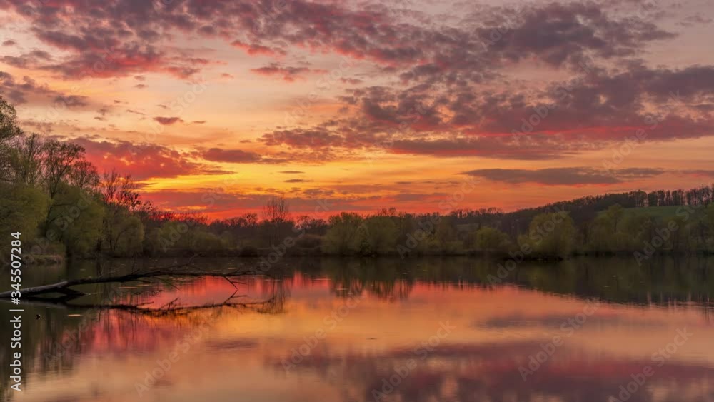 Time-lapse of moving clouds at sunset reflecting above the lake surface dark clouds of black and gray color moving in the sky the sun sets over the horizon Hustopece nad Becvou Czech Republic Time-lapse of moving clouds at sunset reflecting above the lake surface dark clouds of black and gray color moving in the sky the sun sets over the horizon Hustopece nad Becvou Czech Republic