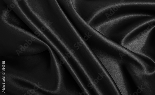 Smooth elegant black silk or satin texture as abstract background. Luxurious background design photo