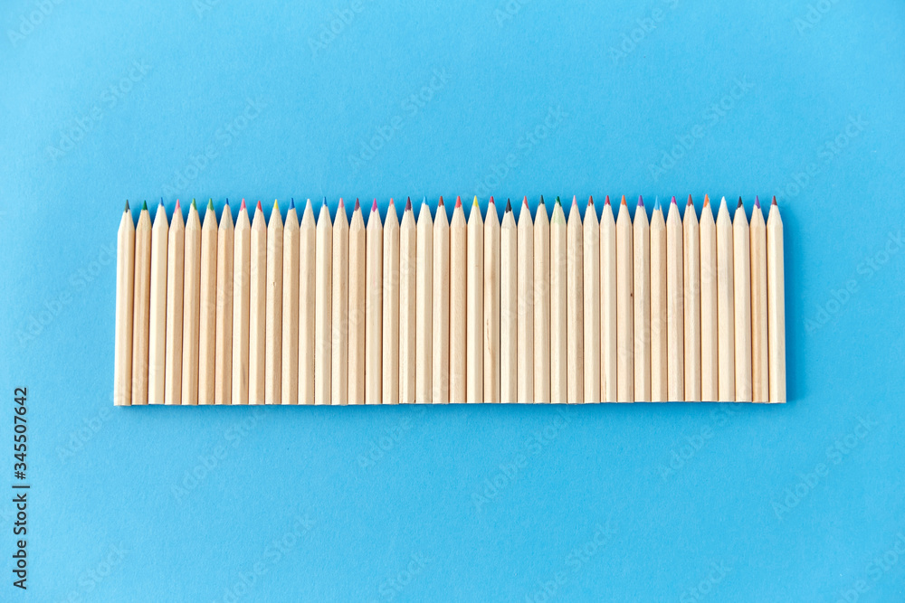 artistic tools, drawing, creativity and object concept - row of many coloring pencils on blue background artistic tools, drawing, creativity and object concept - row of many coloring pencils on blue background