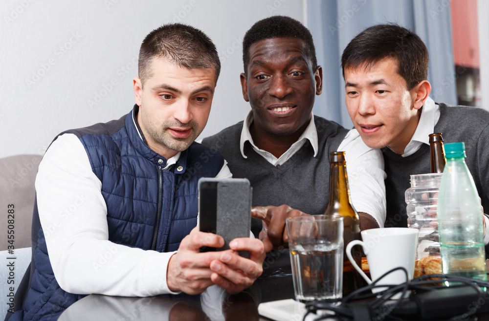 Fototapeta premium Cheerful male friends with phone
