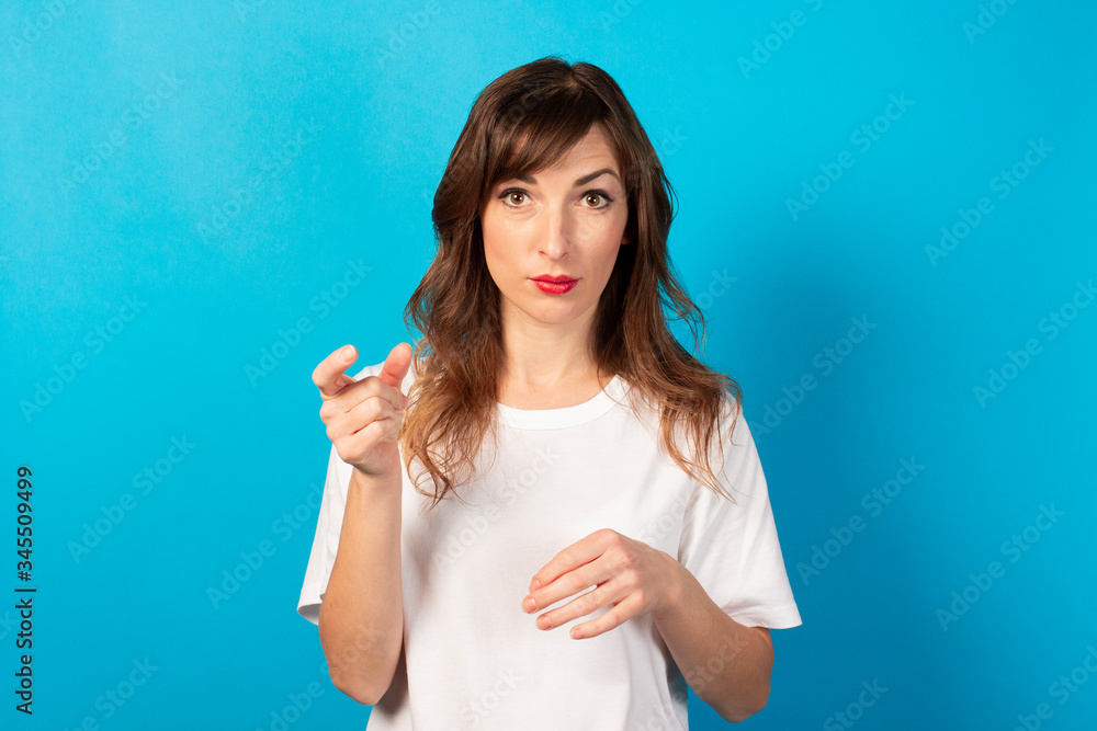 Portrait of a young friendly woman in casual t-shirt on an isolated blue background. Emotional face Portrait of a young friendly woman in casual t-shirt on an isolated blue background. Emotional face