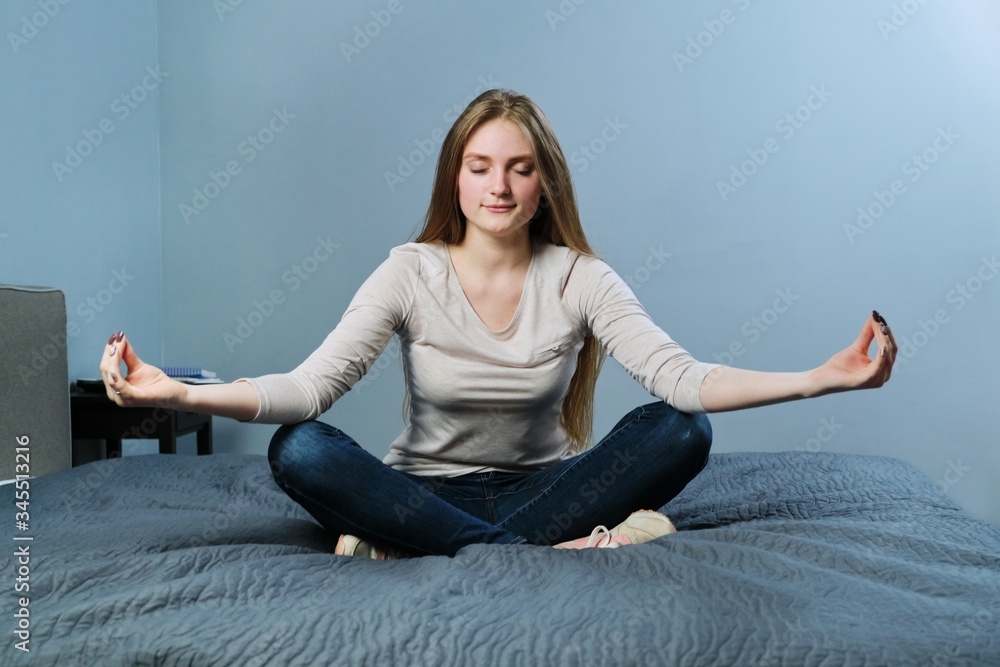 Relaxed young woman sitting at home in bed meditating girl practicing yoga Relaxed young woman sitting at home in bed meditating girl practicing yoga