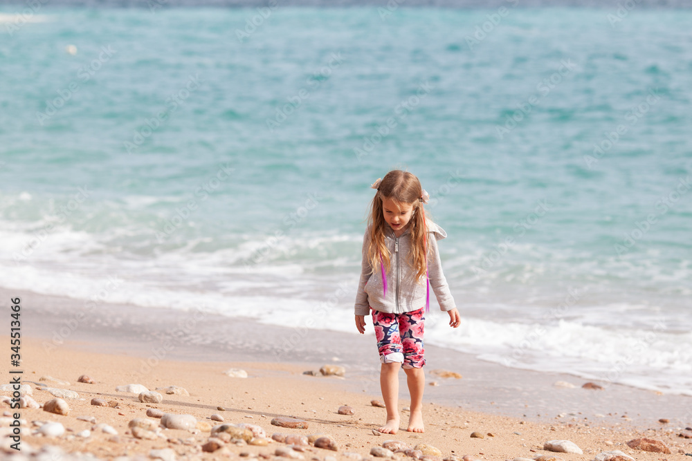 Happy pretty girl walks along the sea coast against the background of the sea, from behind a beautiful landscape