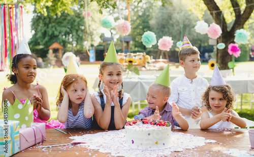 Canvas Print Down syndrome child with friends on birthday party outdoors in garden