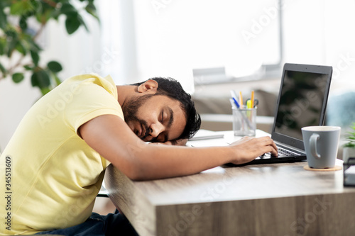 people and lifestyle concept - tired indian man sleeping on table with laptop computer at home