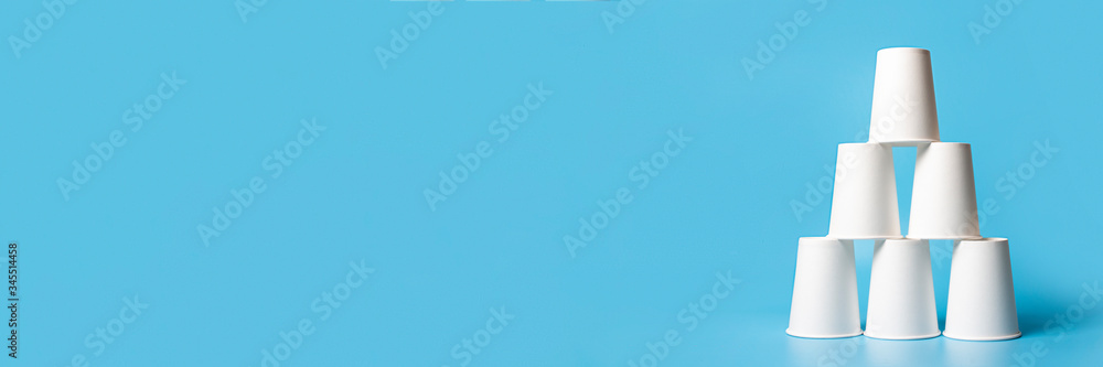 Pyramid-shaped paper cups on a blue background. Concept of corporation ...