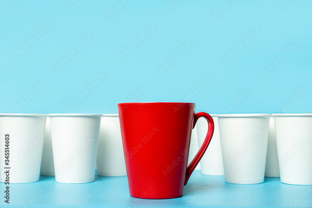 Red cup surrounded by white paper cups on a blue background. Concept boss, unique, friendly team. Copy space Red cup surrounded by white paper cups on a blue background. Concept boss, unique, friendly team. Copy space