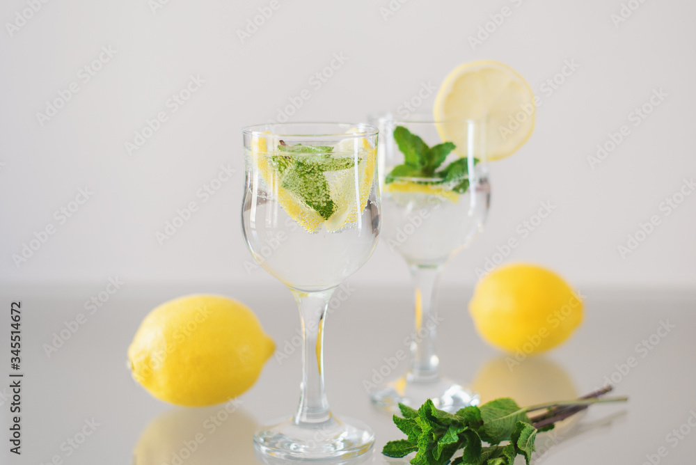 Lemon and mint lemonade. Detox drink with fresh peppermint, lemon fruit and sparkling mineral water on glass table