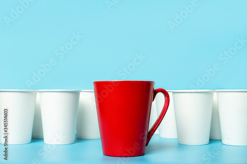 Red cup surrounded by white paper cups on a blue background. Concept boss, unique, friendly team. Copy space