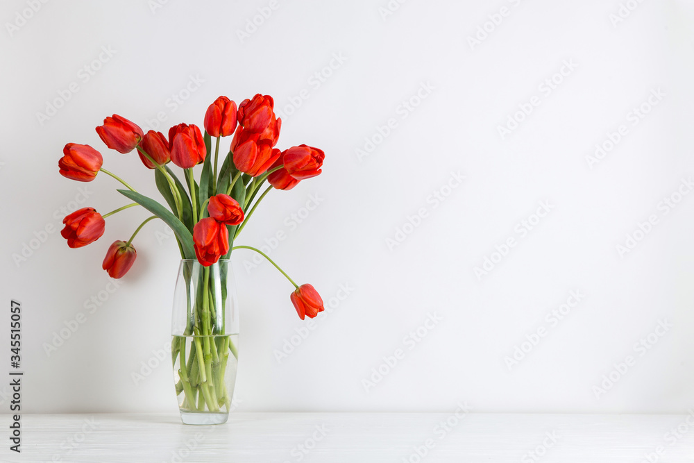 Red tulips in a vase on the table, on a white background. Postcard blank.