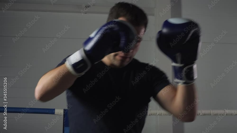 Boxer man in boxing gloves training punches on ring. Fighter thai box man fighting with shadow on boxing ring. Kickboxer training strikes in gym Boxer man in boxing gloves training punches on ring. Fighter thai box man fighting with shadow on boxing ring. Kickboxer training strikes in gym