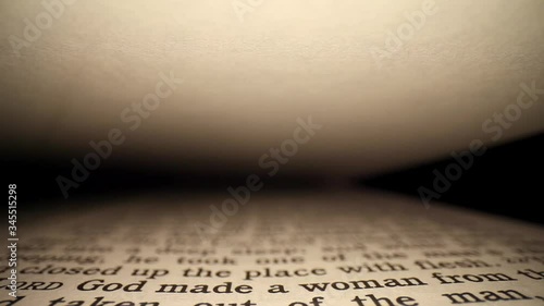 Slowly moving inside Genesis Chapter Two, blank page on top. Wide angle macro view of the page going by several verses dealing with the naming of the animals and the garden of Eden.