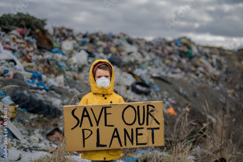 Small child holding placard poster on landfill, environmental pollution concept. photo