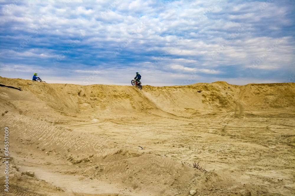 Motorcyclist on a sand quarry against the sky with clouds in the summer
